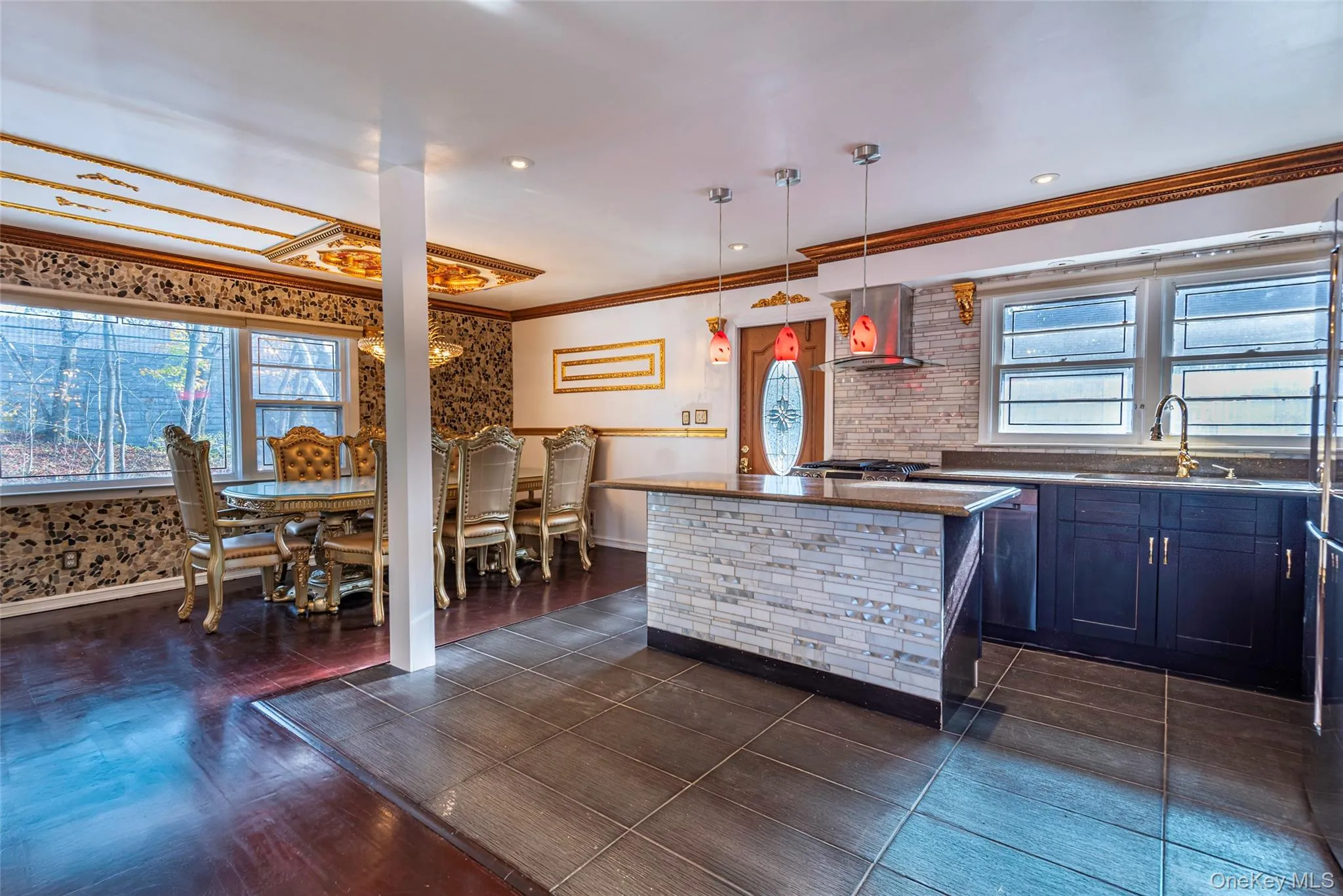 Kitchen with pendant lighting, ornamental molding, wall chimney range hood, and a center island Kitchen with pendant lighting, ornamental molding, wall chimney range hood, and a center island