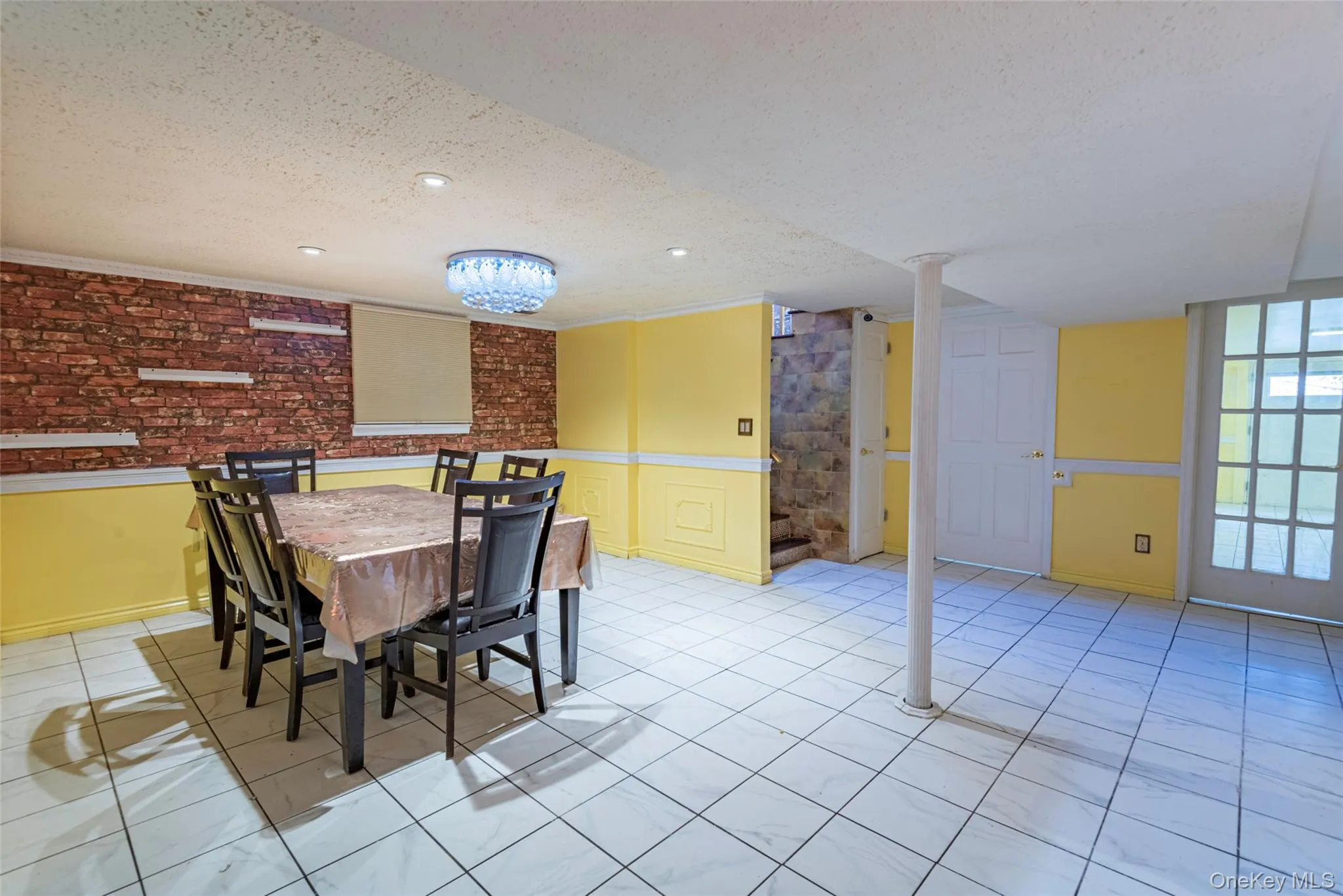 Dining area with a textured ceiling, light tile patterned floors, and a wainscoted wall Dining area with a textured ceiling, light tile patterned floors, and a wainscoted wall