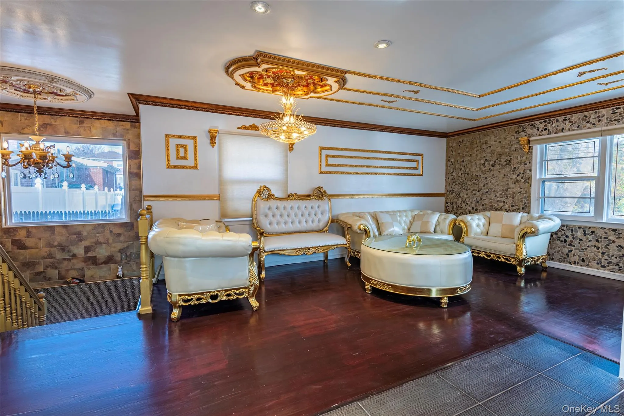 Living room with a chandelier, crown molding, wood finished floors, wallpapered walls, and a wainscoted wall Living room with a chandelier, crown molding, wood finished floors, wallpapered walls, and a wainscoted wall