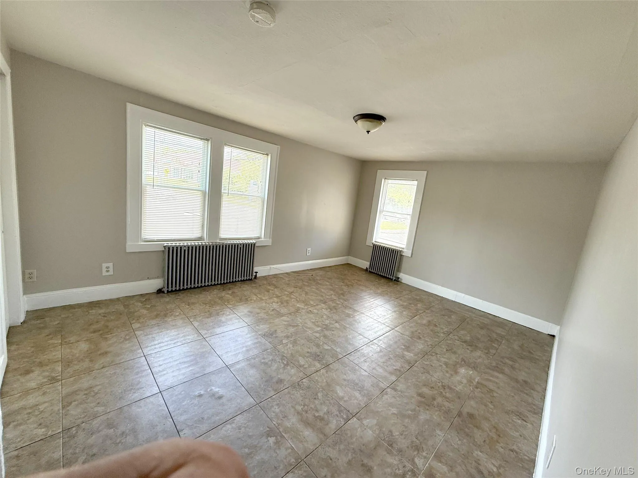 Unfurnished studio / bedroom / living-room featuring radiator and tile patterned floors Unfurnished studio / bedroom / living-room featuring radiator and tile patterned floors