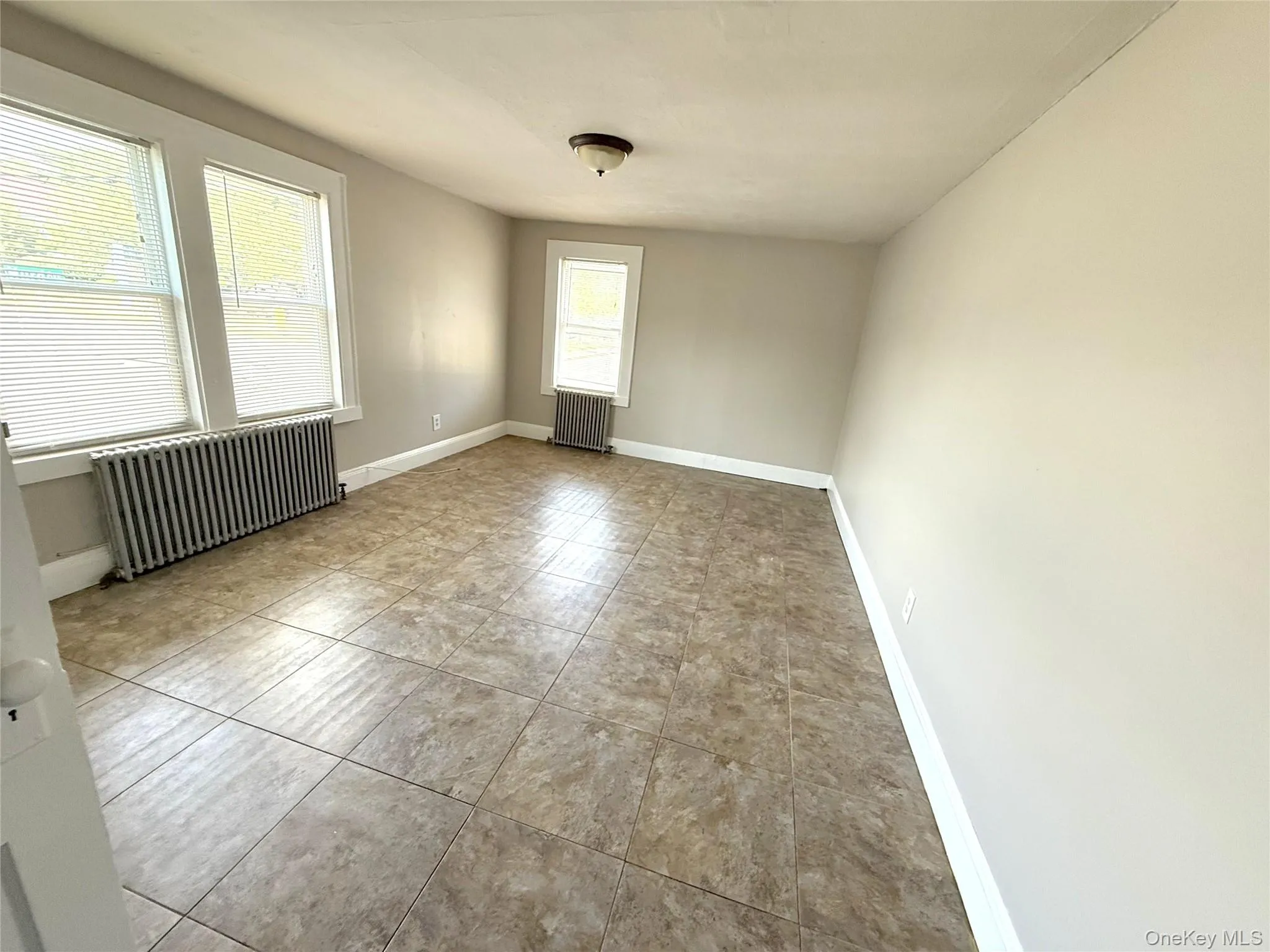 Unfurnished studio / bedroom / living-room featuring radiator and tile patterned floors Unfurnished studio / bedroom / living-room featuring radiator and tile patterned floors
