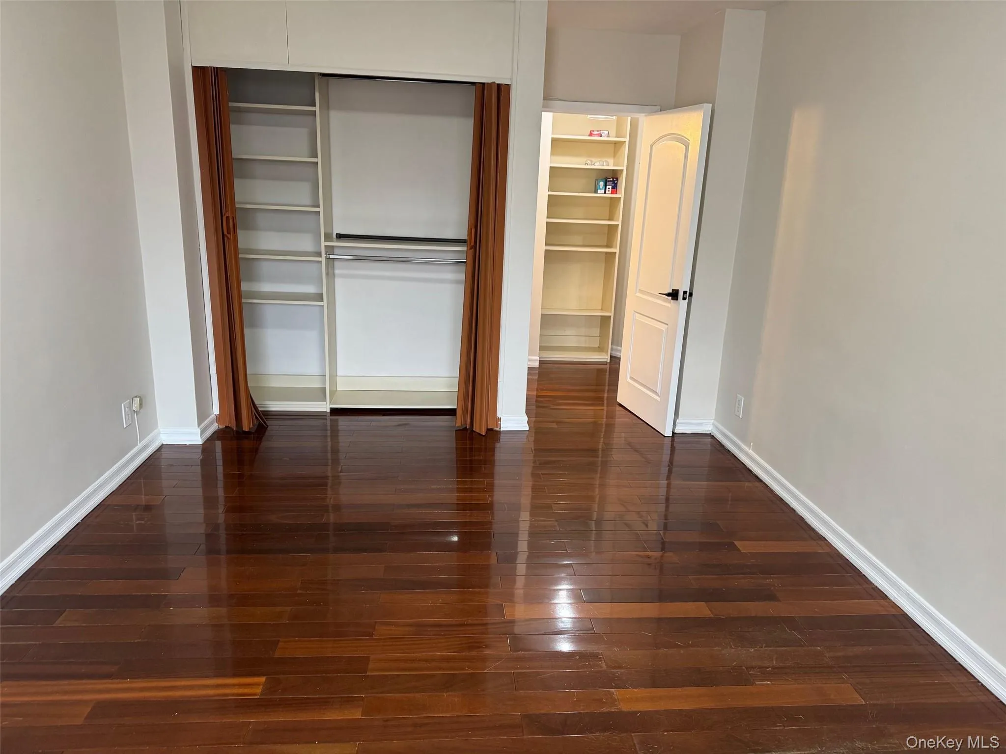 Unfurnished bedroom featuring dark wood-style flooring and a closet Unfurnished bedroom featuring dark wood-style flooring and a closet