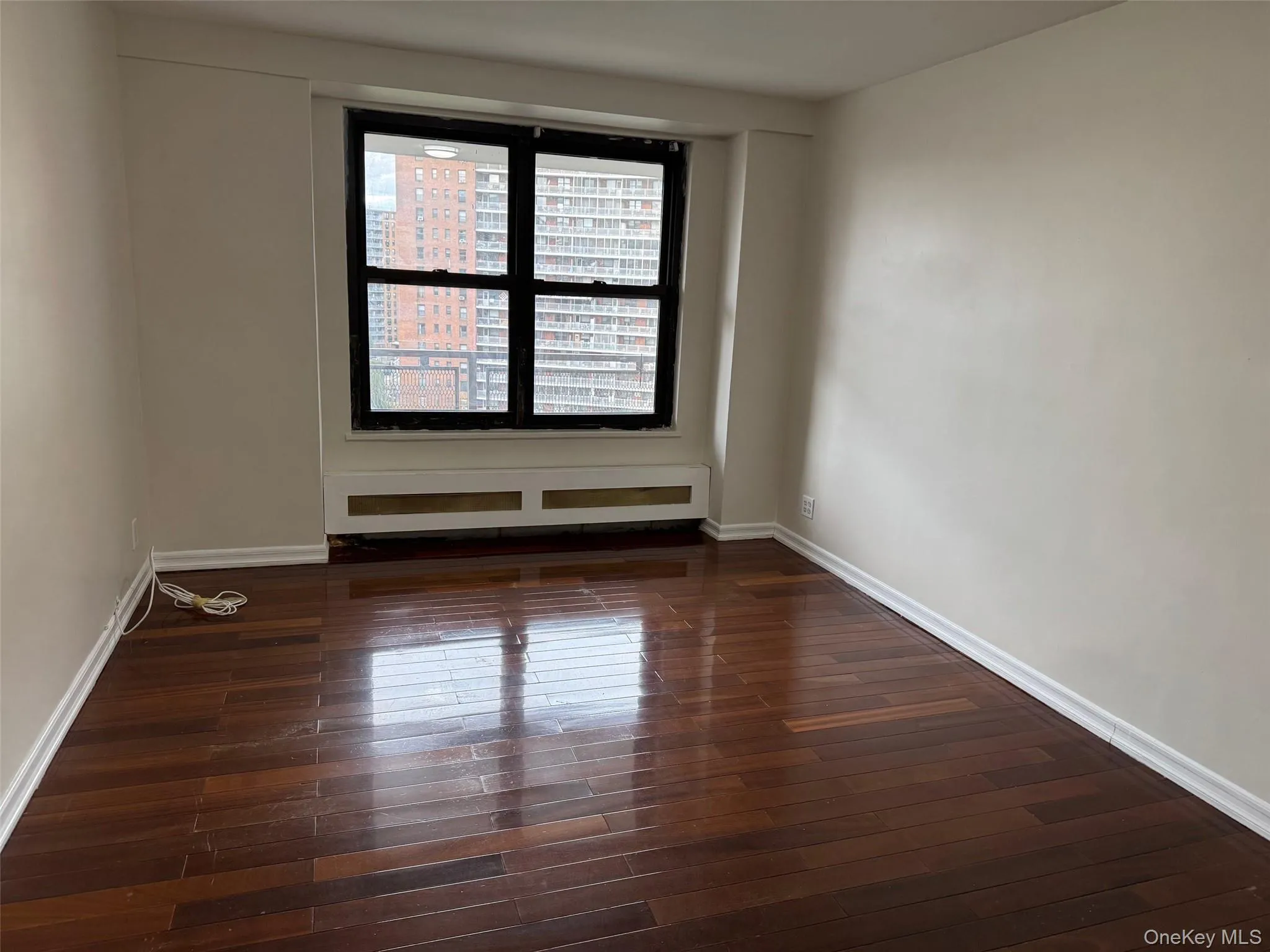 Unfurnished room featuring dark wood finished floors and a baseboard heating unit Unfurnished room featuring dark wood finished floors and a baseboard heating unit