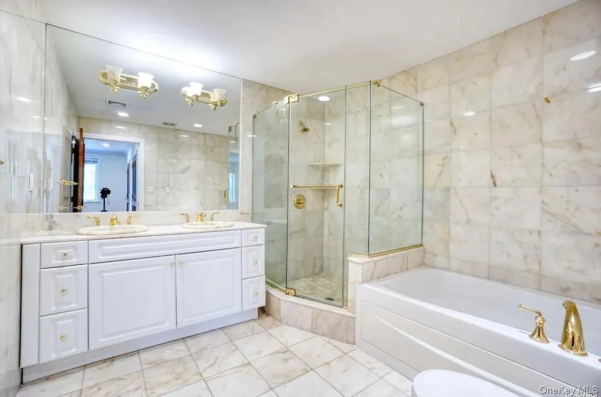 Bathroom featuring tile walls, a bath, double vanity, and a shower stall Bathroom featuring tile walls, a bath, double vanity, and a shower stall