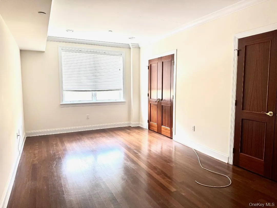Unfurnished bedroom with ornamental molding, dark wood-type flooring, and a closet Unfurnished bedroom with ornamental molding, dark wood-type flooring, and a closet