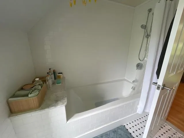 Bathroom featuring shower / tub combination and wood finished floors Bathroom featuring shower / tub combination and wood finished floors