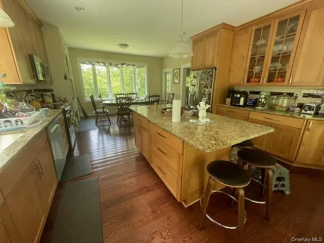 Kitchen with appliances with stainless steel finishes, dark wood finished floors, a kitchen island, glass insert cabinets, and light stone counters Kitchen with appliances with stainless steel finishes, dark wood finished floors, a kitchen island, glass insert cabinets, and light stone counters