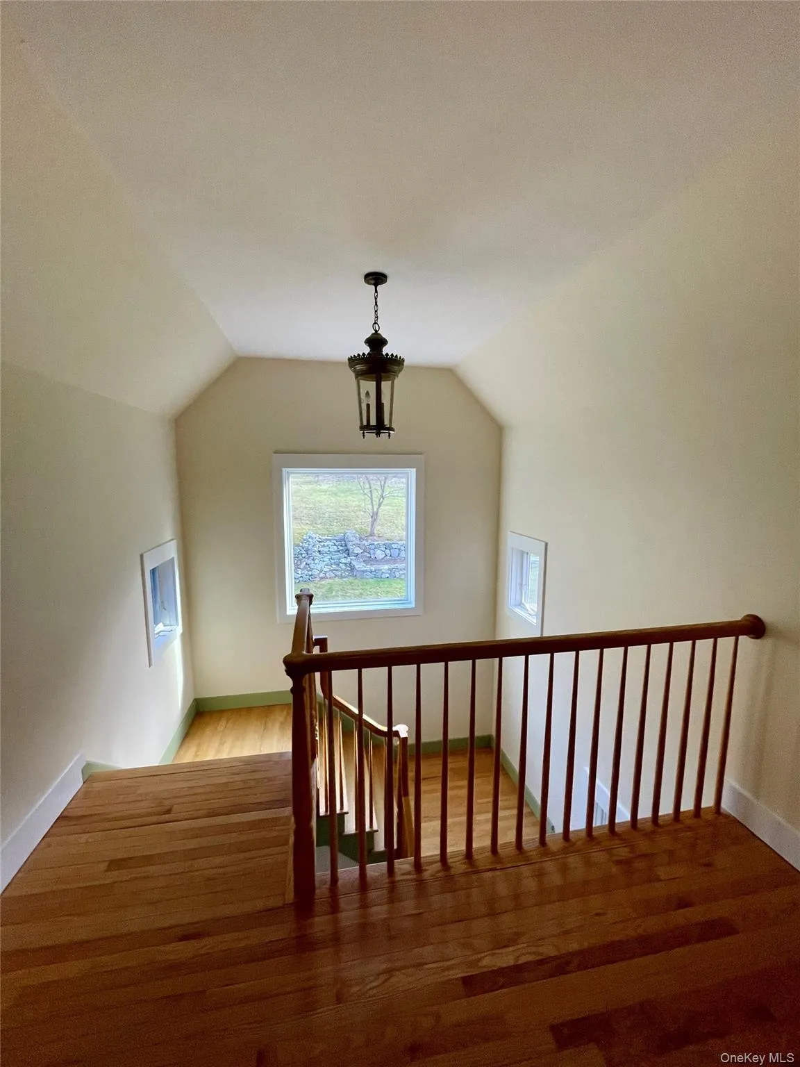 Staircase featuring lofted ceiling and wood finished floors Staircase featuring lofted ceiling and wood finished floors