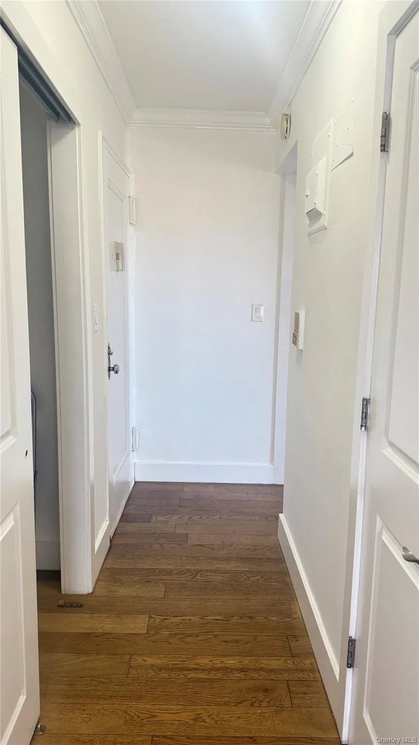 Corridor featuring dark wood finished floors and ornamental molding Corridor featuring dark wood finished floors and ornamental molding