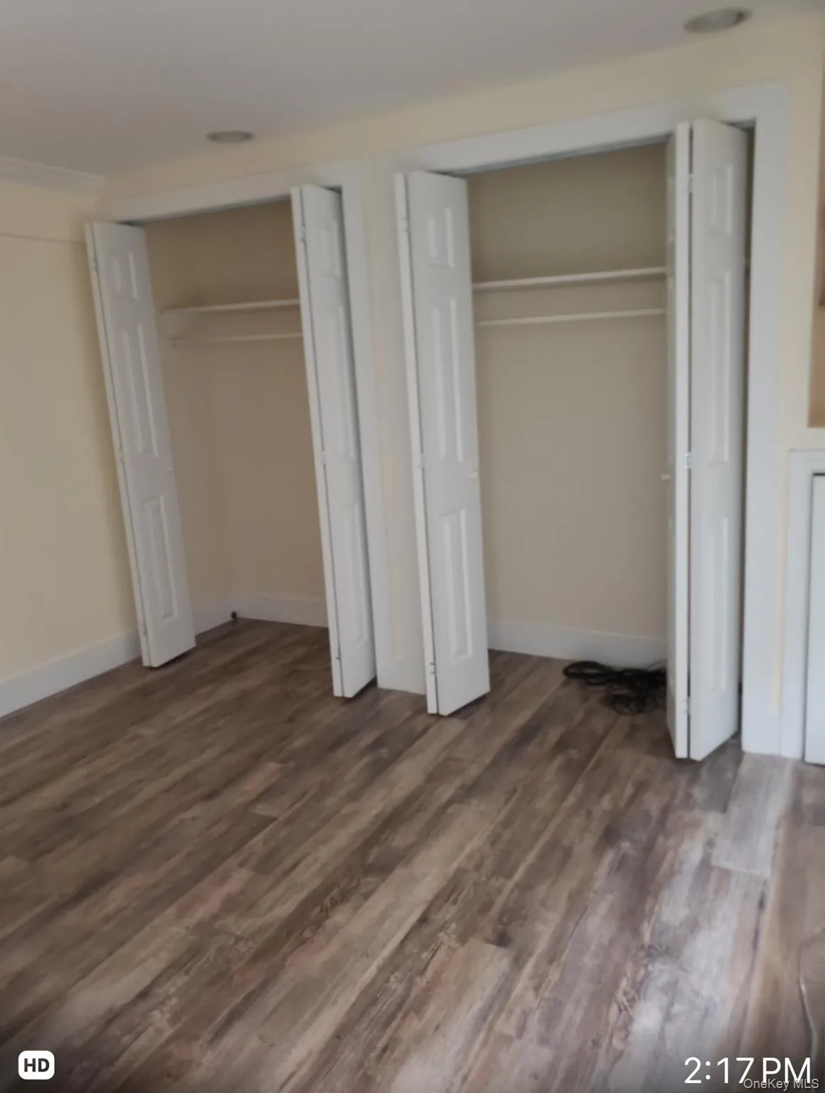 Unfurnished bedroom with two closets and dark wood-style flooring Unfurnished bedroom with two closets and dark wood-style flooring