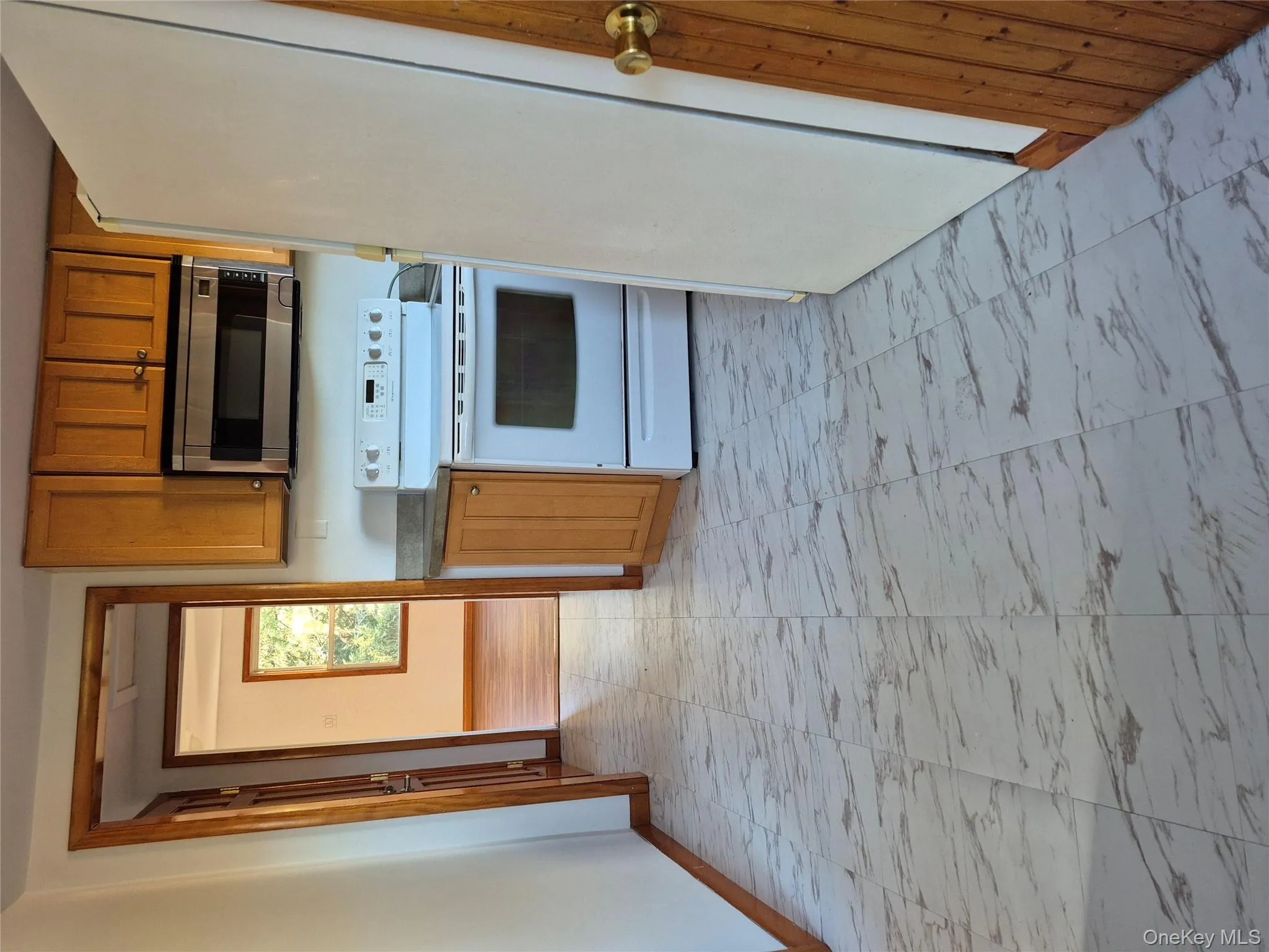 Kitchen featuring brown cabinetry, stove, light marble finish floors, and refrigerator Kitchen featuring brown cabinetry, stove, light marble finish floors, and refrigerator
