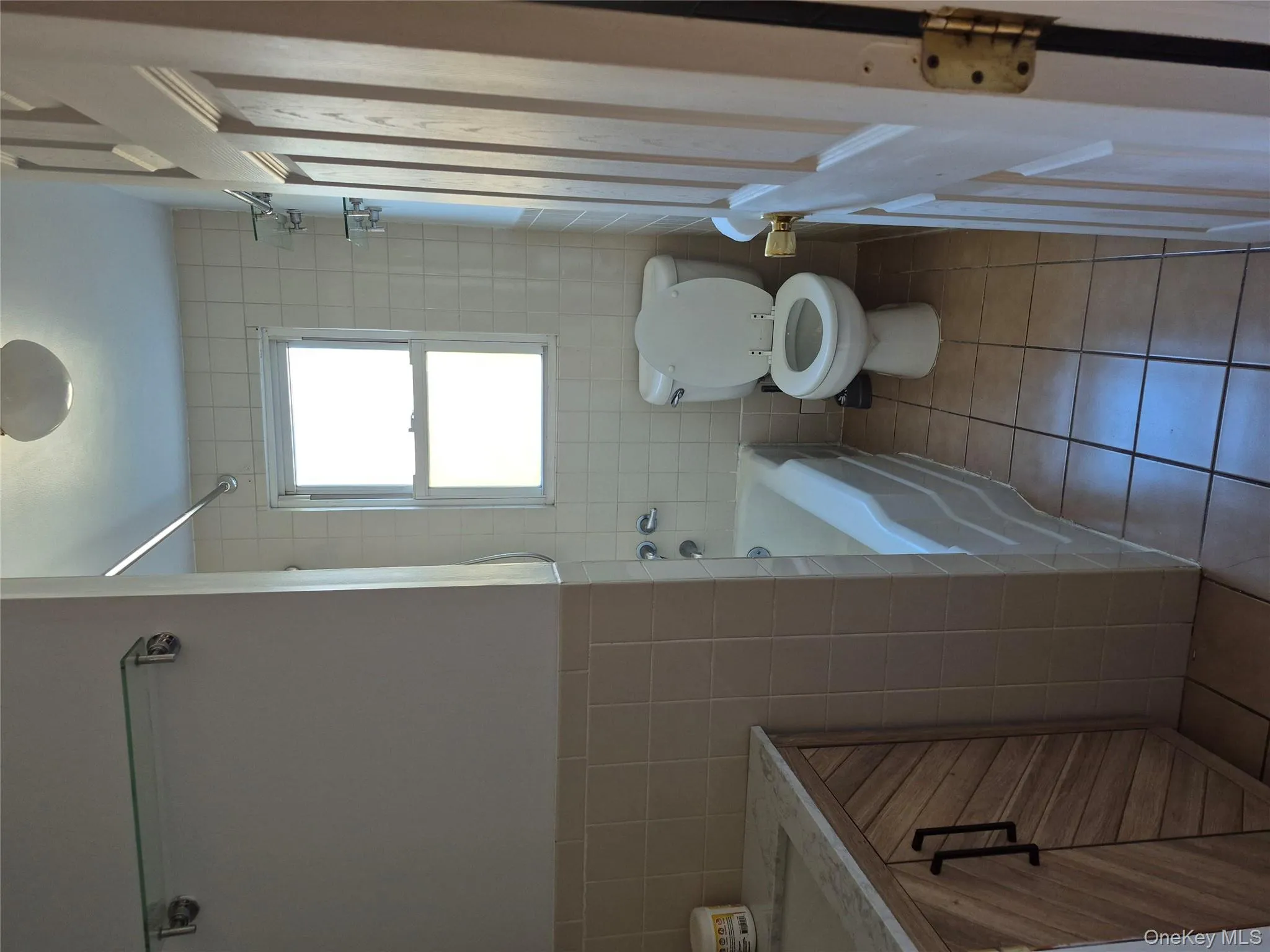 Full bath featuring tile walls, light tile patterned floors, vanity, and shower / bathtub combination Full bath featuring tile walls, light tile patterned floors, vanity, and shower / bathtub combination