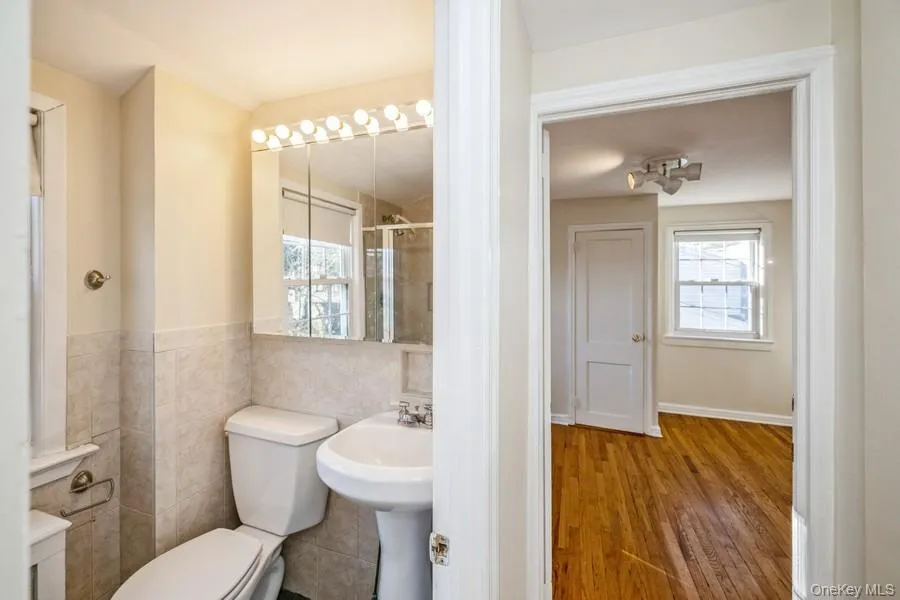Bathroom with plenty of natural light, wood finished floors, a shower stall, and tile walls Bathroom with plenty of natural light, wood finished floors, a shower stall, and tile walls