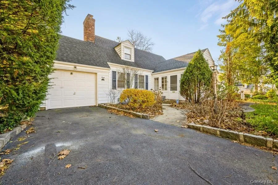 Cape cod house featuring roof with shingles, driveway, a chimney, and an attached garage Cape cod house featuring roof with shingles, driveway, a chimney, and an attached garage