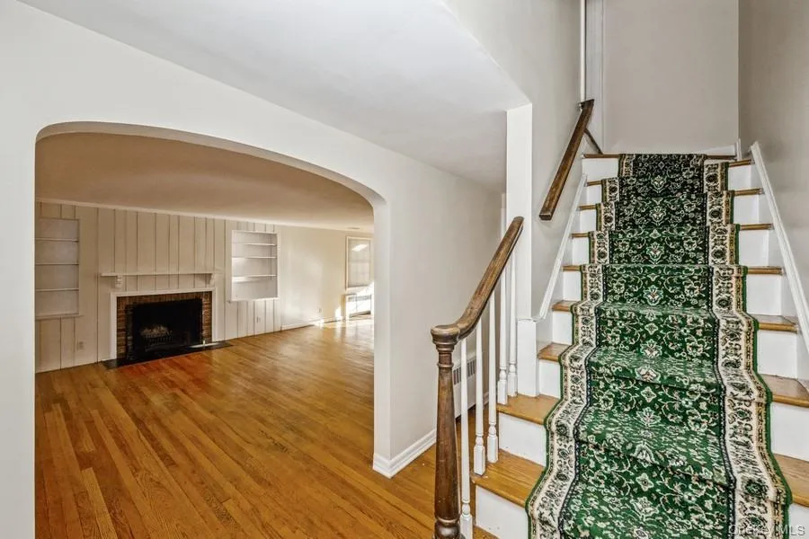Stairs featuring arched walkways, wood finished floors, a brick fireplace, and built in features Stairs featuring arched walkways, wood finished floors, a brick fireplace, and built in features