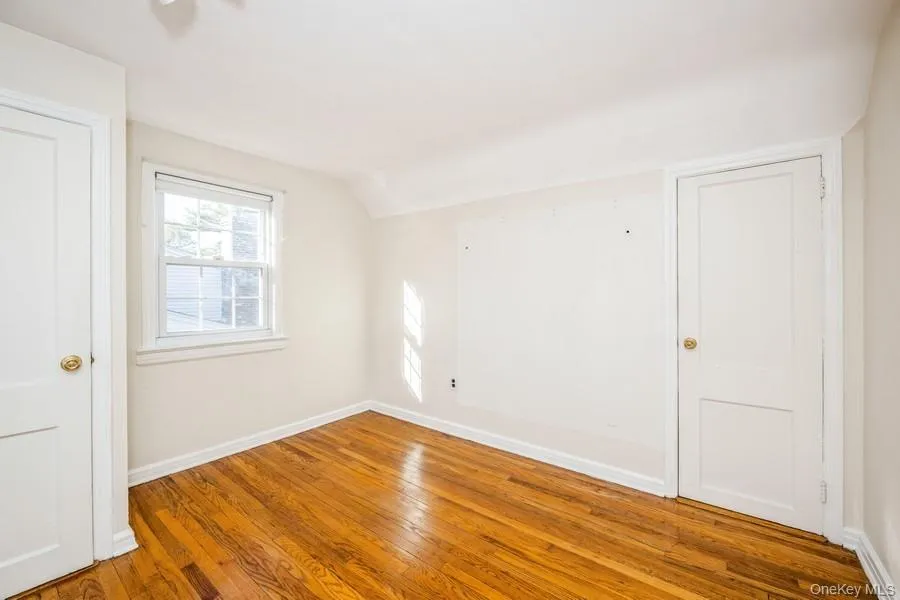 Unfurnished room with hardwood / wood-style flooring and lofted ceiling Unfurnished room with hardwood / wood-style flooring and lofted ceiling