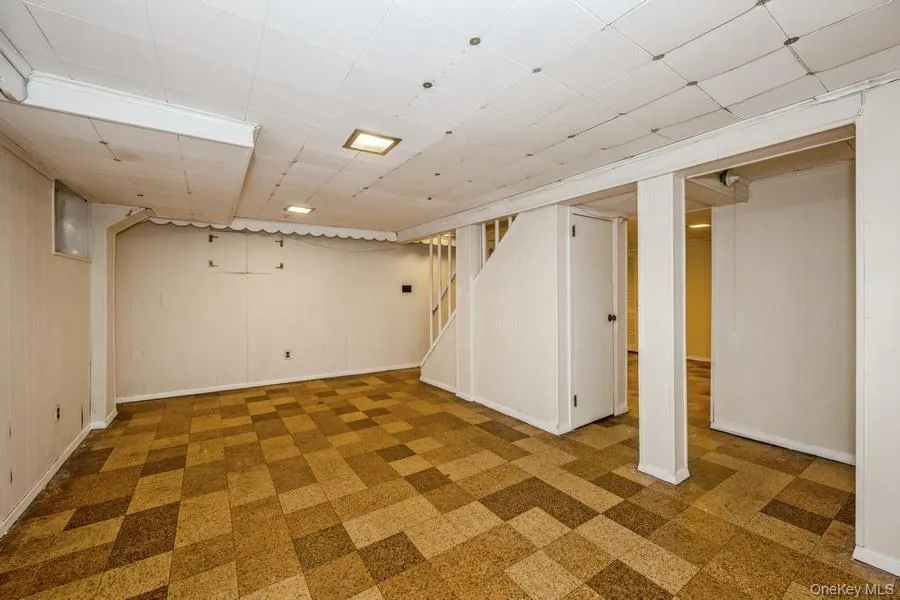 Finished basement featuring tile patterned floors, a paneled ceiling, and stairs Finished basement featuring tile patterned floors, a paneled ceiling, and stairs