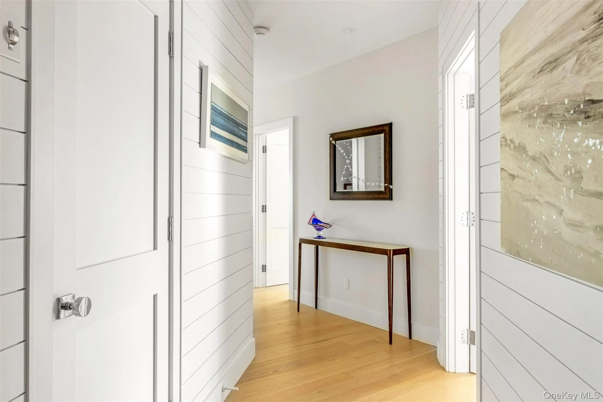Corridor featuring light wood-type flooring and wooden walls Corridor featuring light wood-type flooring and wooden walls