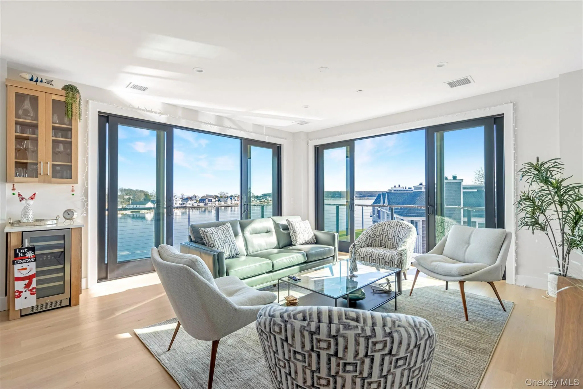 Living area featuring a water view, wine cooler, light wood-style flooring, and a bar Living area featuring a water view, wine cooler, light wood-style flooring, and a bar