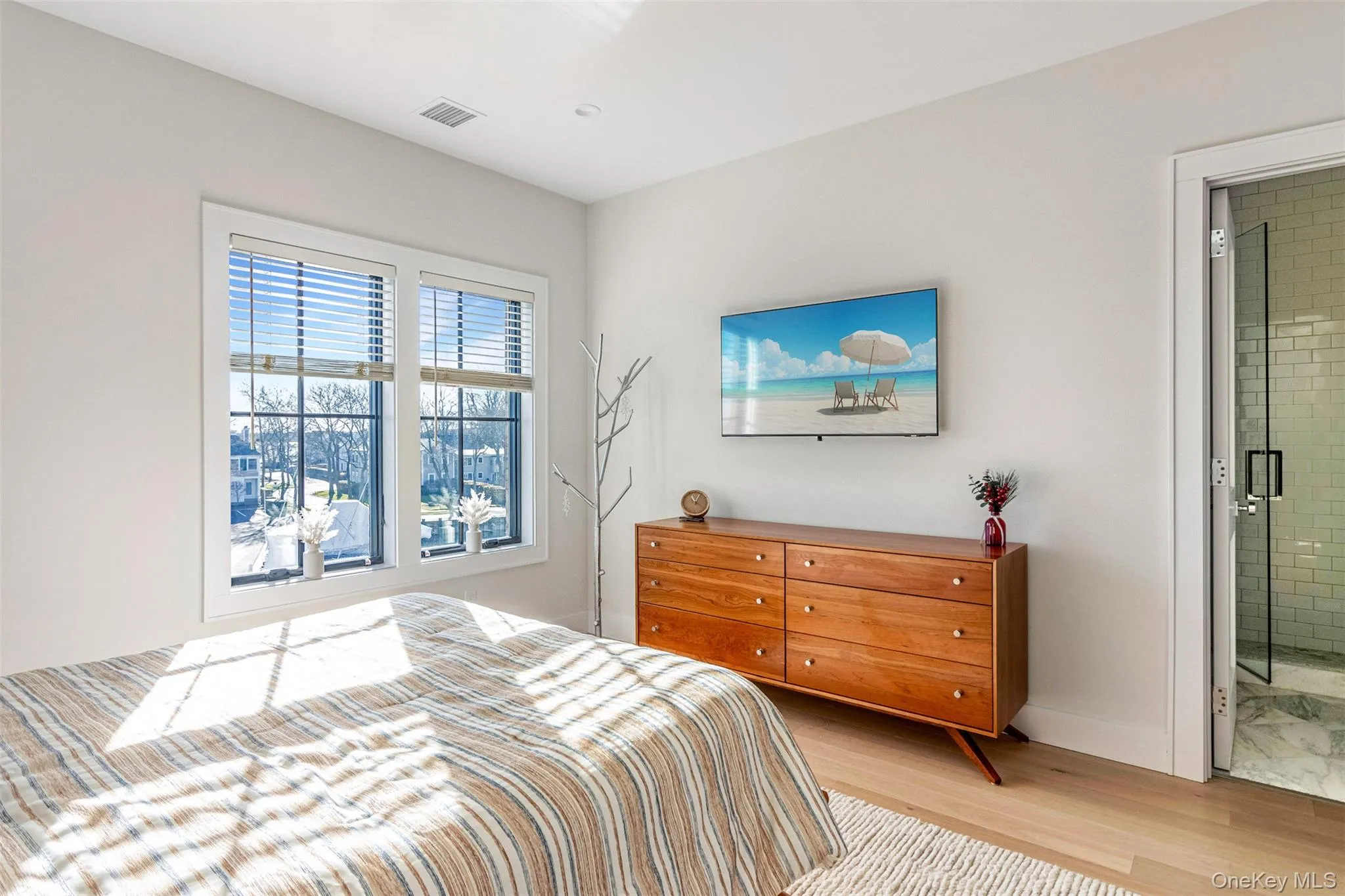 Bedroom featuring light wood-style flooring and connected bathroom Bedroom featuring light wood-style flooring and connected bathroom