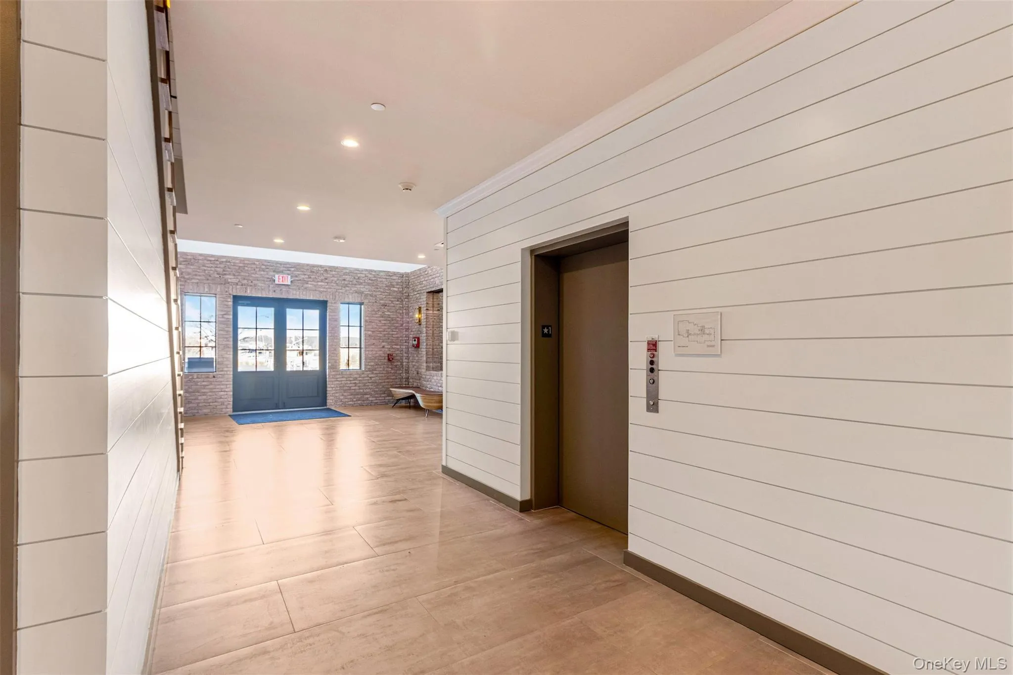 Hallway with recessed lighting, elevator, crown molding, and brick wall Hallway with recessed lighting, elevator, crown molding, and brick wall