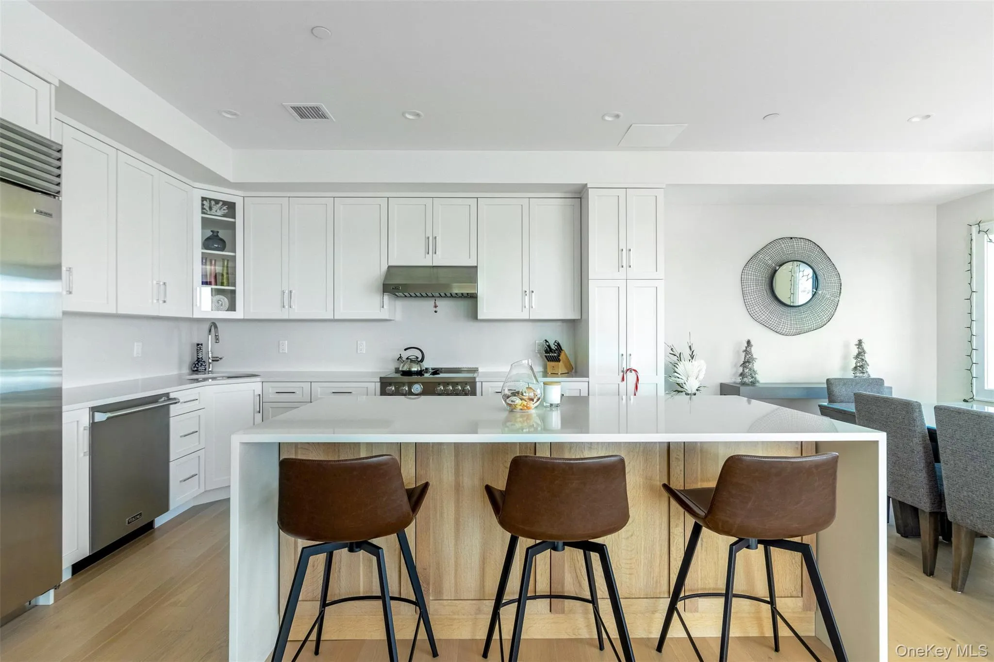 Kitchen with white cabinetry, a center island, light stone counters, appliances with stainless steel finishes, and recessed lighting Kitchen with white cabinetry, a center island, light stone counters, appliances with stainless steel finishes, and recessed lighting