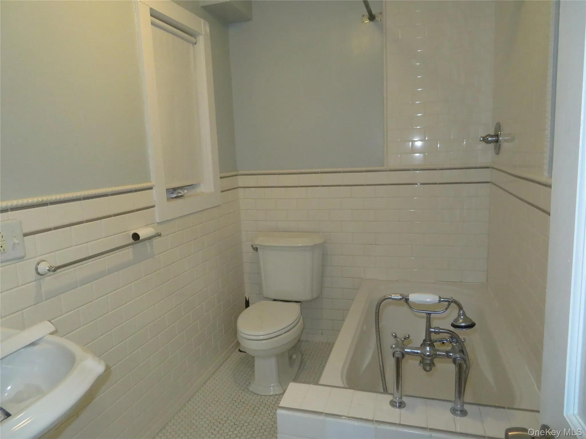 Bathroom with tile walls, a wainscoted wall, tile patterned flooring, and tiled shower / bath combo Bathroom with tile walls, a wainscoted wall, tile patterned flooring, and tiled shower / bath combo
