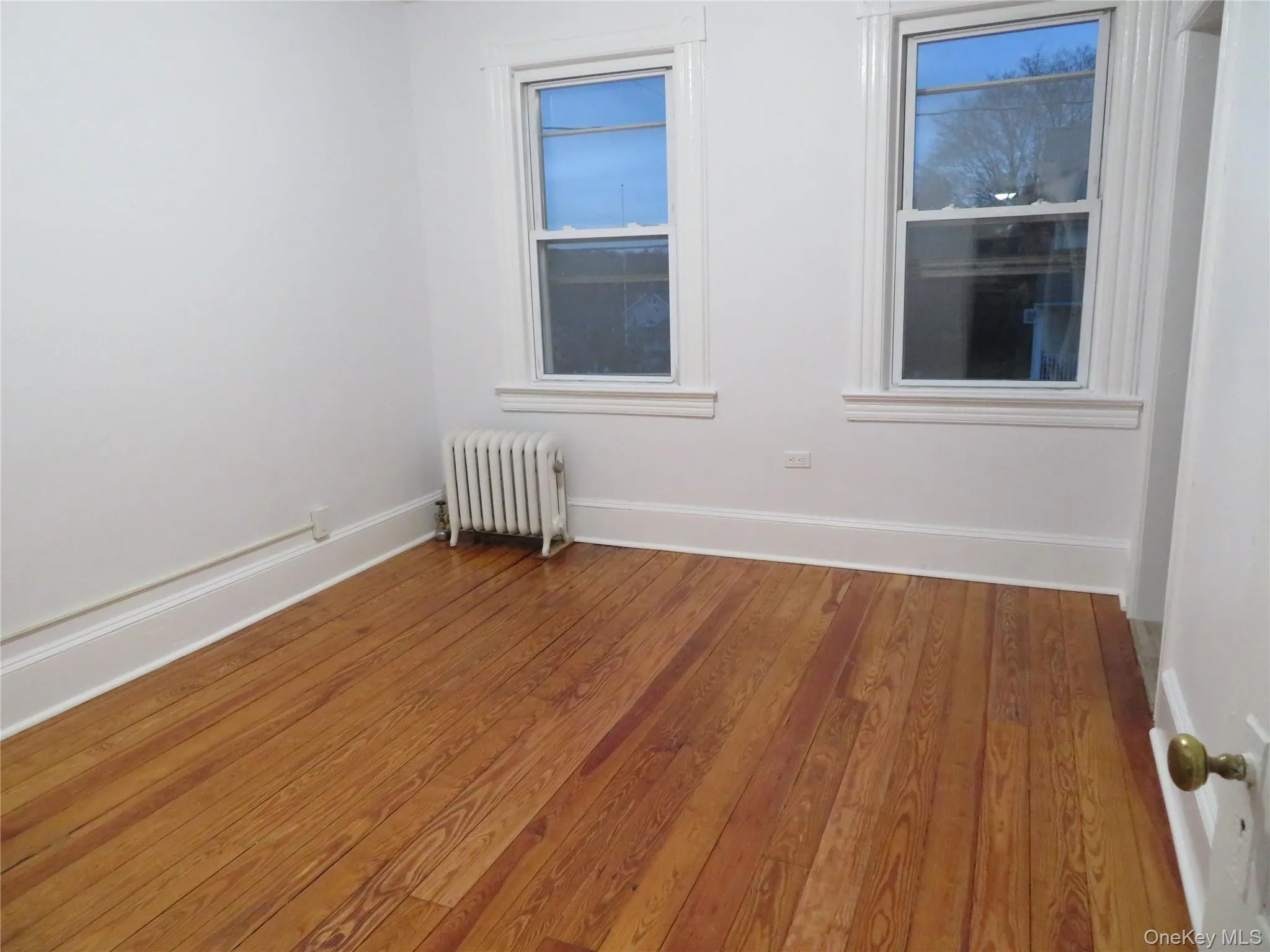 Spare room with light wood finished floors and radiator Spare room with light wood finished floors and radiator