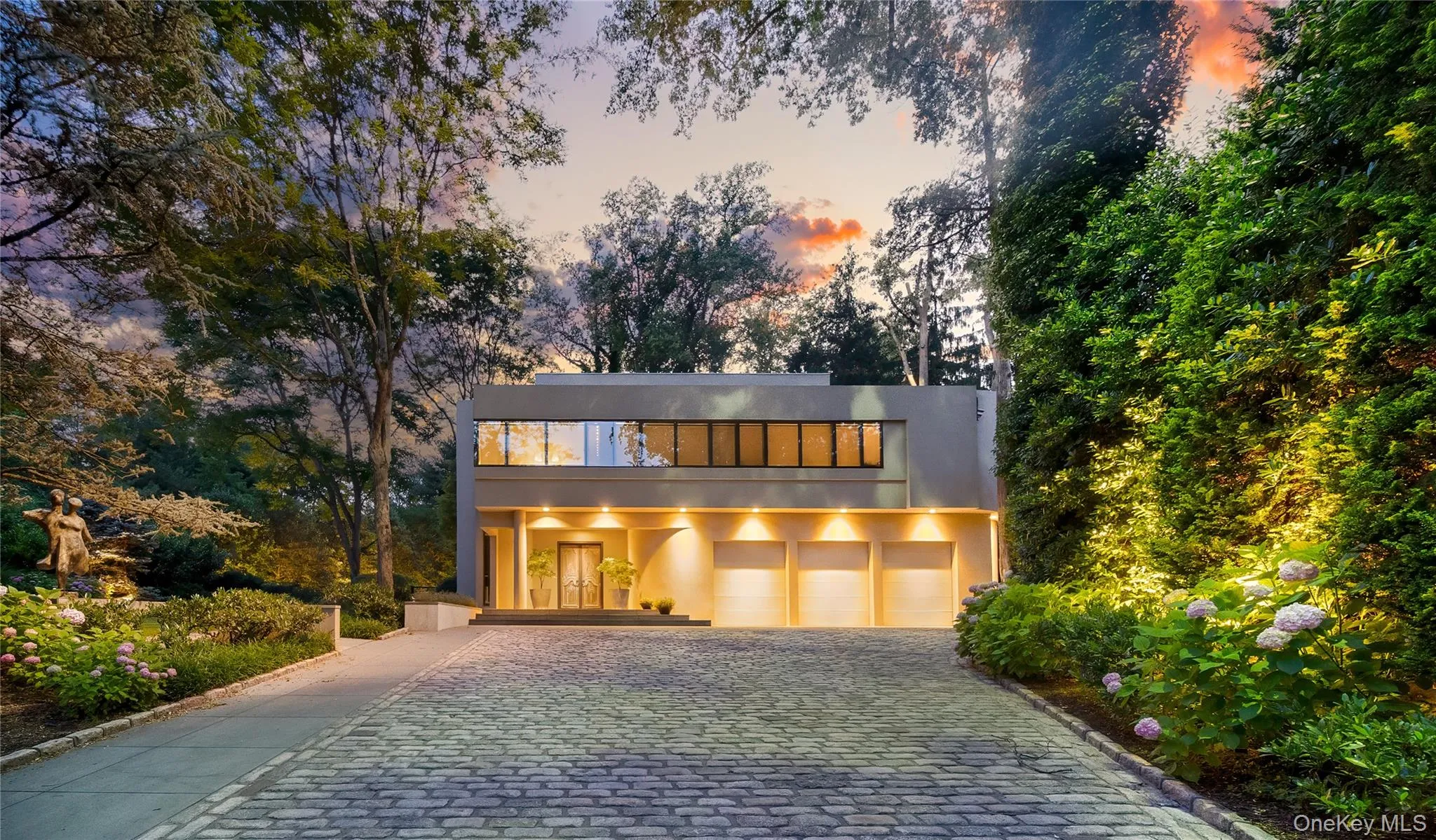 Contemporary home with stucco siding, decorative driveway, and a garage Contemporary home with stucco siding, decorative driveway, and a garage