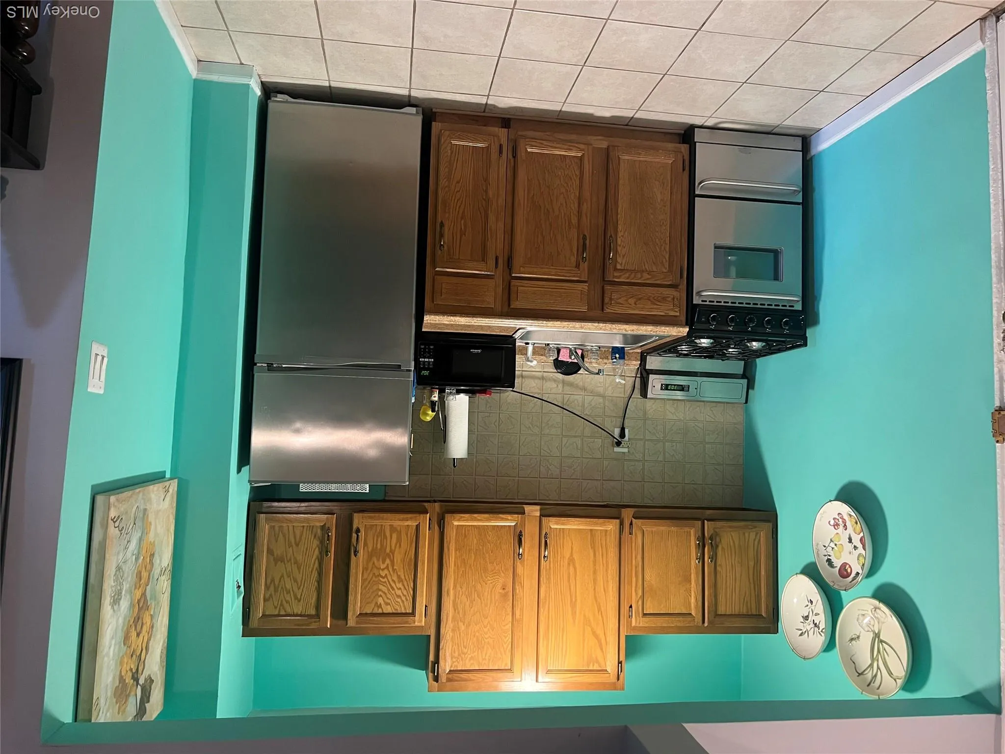 Kitchen featuring stainless steel appliances, backsplash, brown cabinets, and light countertops Kitchen featuring stainless steel appliances, backsplash, brown cabinets, and light countertops