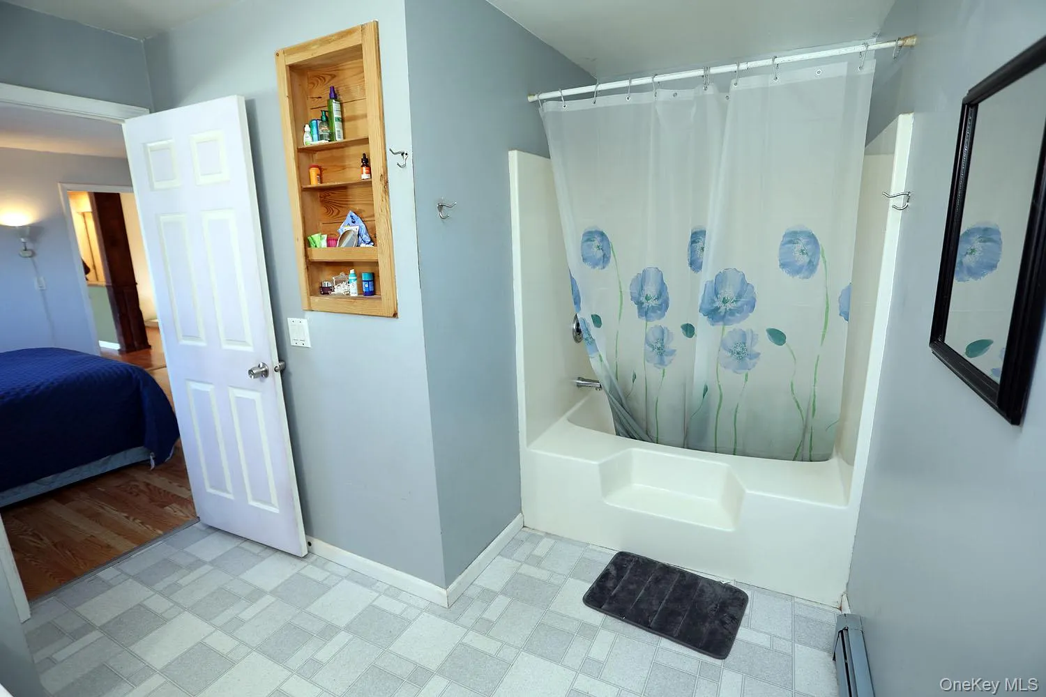 Ensuite bathroom featuring shower / bathtub combination with curtain, tile patterned floors, and a baseboard radiator Ensuite bathroom featuring shower / bathtub combination with curtain, tile patterned floors, and a baseboard radiator