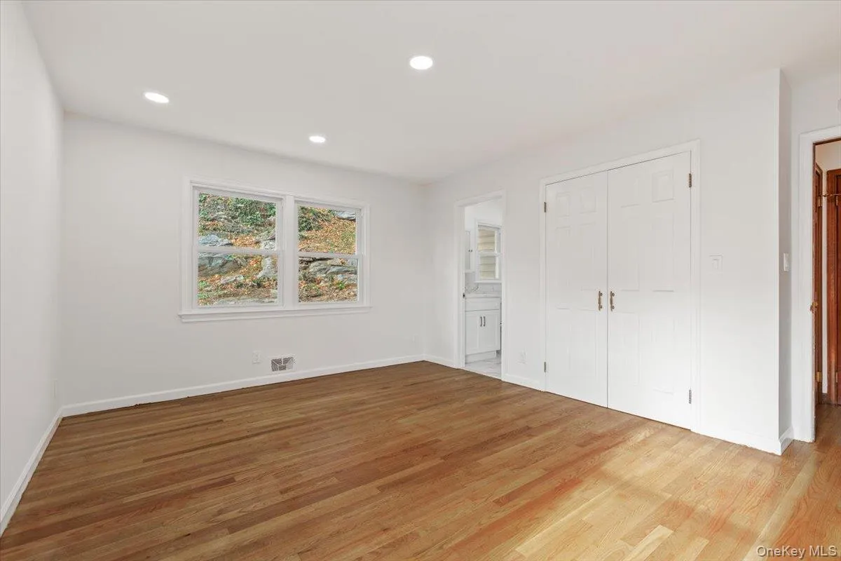 Unfurnished bedroom with recessed lighting, wood finished floors, connected bathroom, and a closet Unfurnished bedroom with recessed lighting, wood finished floors, connected bathroom, and a closet