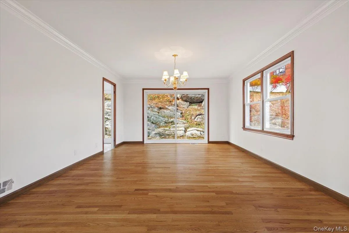 Unfurnished dining area with a chandelier, ornamental molding, and wood finished floors Unfurnished dining area with a chandelier, ornamental molding, and wood finished floors