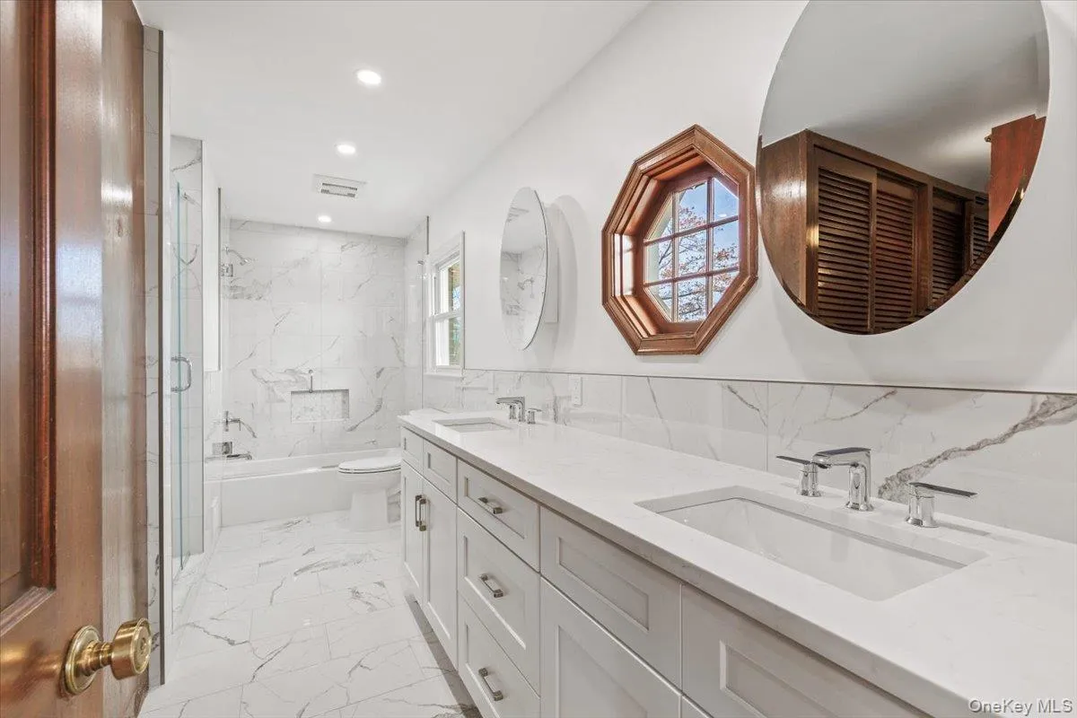 Bathroom with light marble finish floors, double vanity, tile walls, and recessed lighting Bathroom with light marble finish floors, double vanity, tile walls, and recessed lighting
