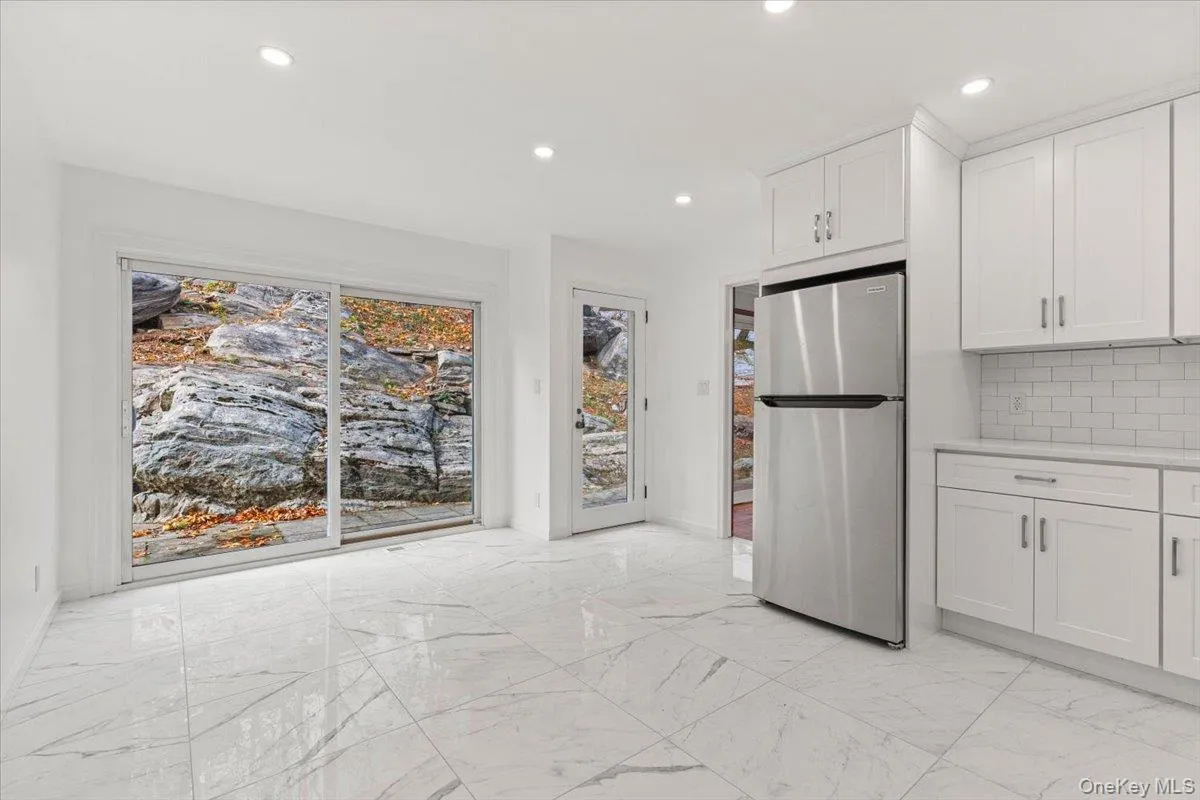 Kitchen featuring freestanding refrigerator, light marble finish floors, decorative backsplash, white cabinetry, and recessed lighting Kitchen featuring freestanding refrigerator, light marble finish floors, decorative backsplash, white cabinetry, and recessed lighting