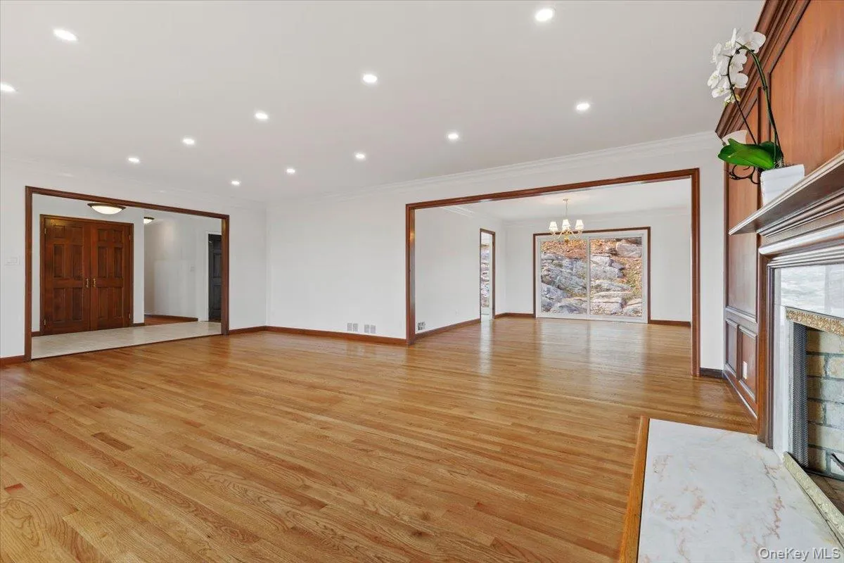 Unfurnished living room with light wood-style floors, ornamental molding, healthy amount of natural light, a fireplace, and recessed lighting Unfurnished living room with light wood-style floors, ornamental molding, healthy amount of natural light, a fireplace, and recessed lighting