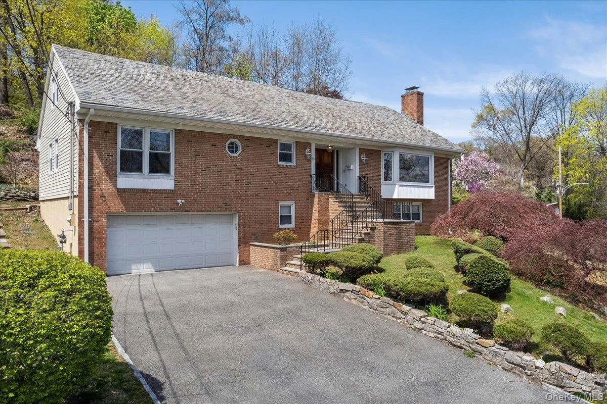 View of front of home with a chimney, driveway, brick siding, and an attached garage View of front of home with a chimney, driveway, brick siding, and an attached garage