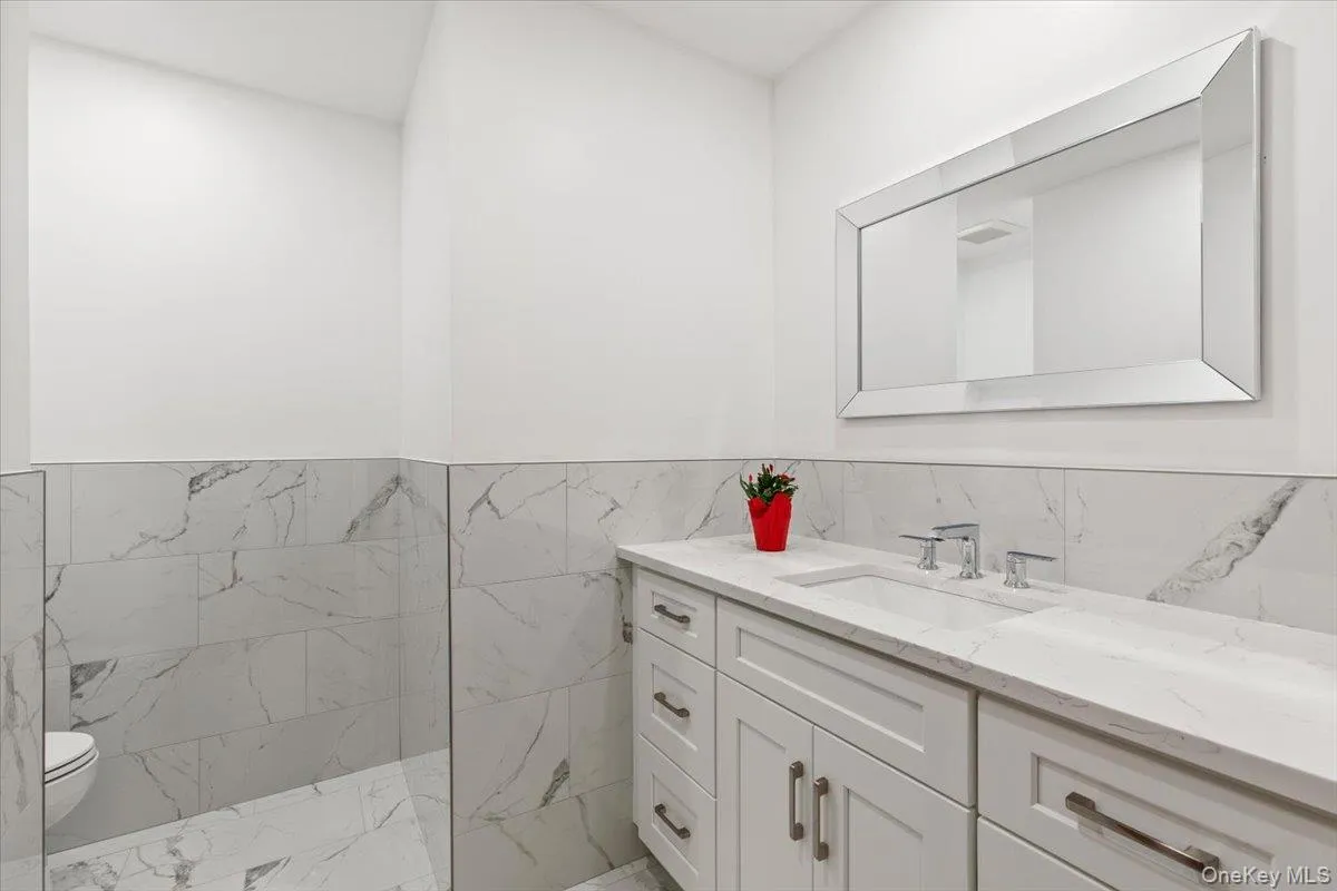 Bathroom with vanity, tile walls, and a wainscoted wall Bathroom with vanity, tile walls, and a wainscoted wall