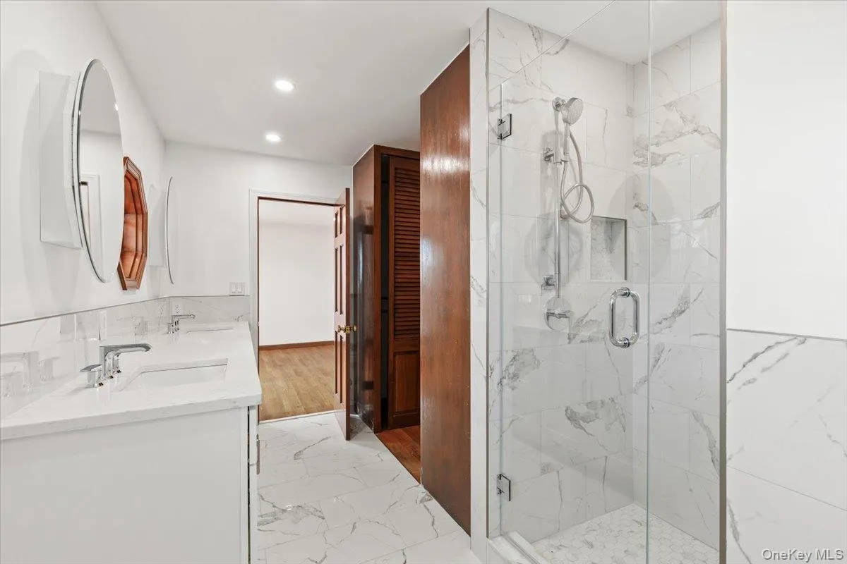 Bathroom with double vanity, light marble finish flooring, recessed lighting, and a marble finish shower Bathroom with double vanity, light marble finish flooring, recessed lighting, and a marble finish shower