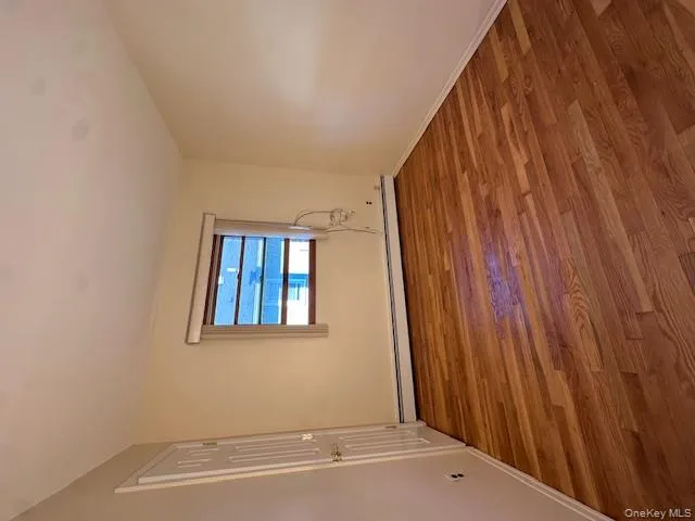 Unfurnished room with wood finished floors and a baseboard radiator Unfurnished room with wood finished floors and a baseboard radiator