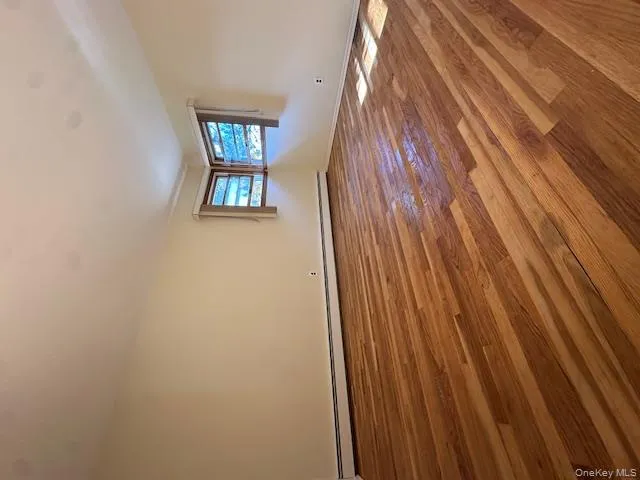 Empty room featuring wood finished floors and a baseboard radiator Empty room featuring wood finished floors and a baseboard radiator