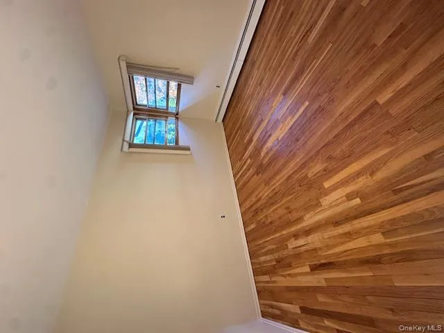 Empty room featuring baseboard heating and wood finished floors Empty room featuring baseboard heating and wood finished floors