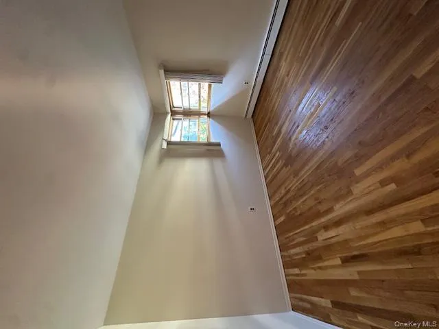 Empty room featuring a baseboard radiator and dark wood finished floors Empty room featuring a baseboard radiator and dark wood finished floors
