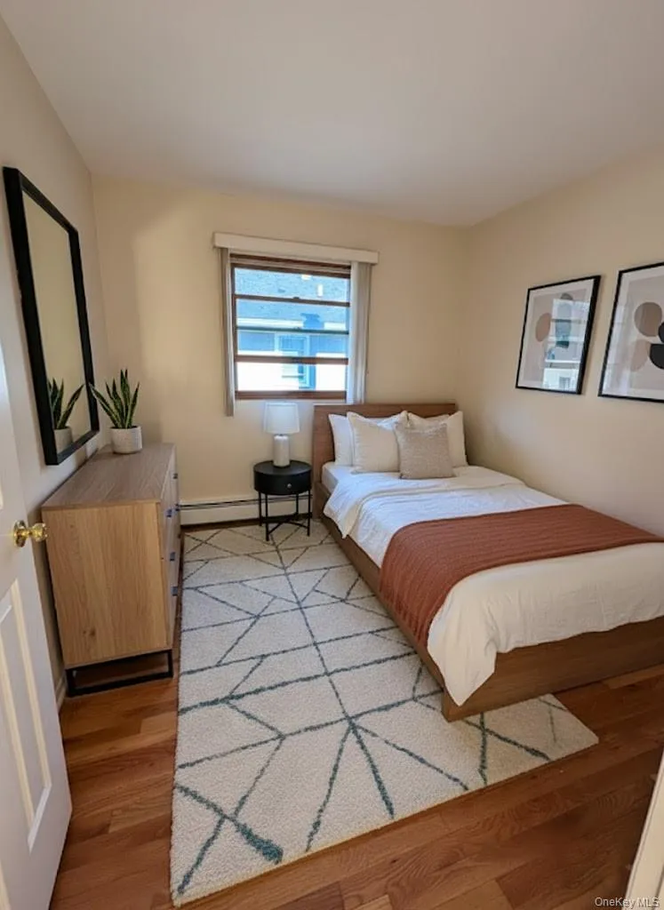 Bedroom with light wood finished floors and baseboard heating Bedroom with light wood finished floors and baseboard heating