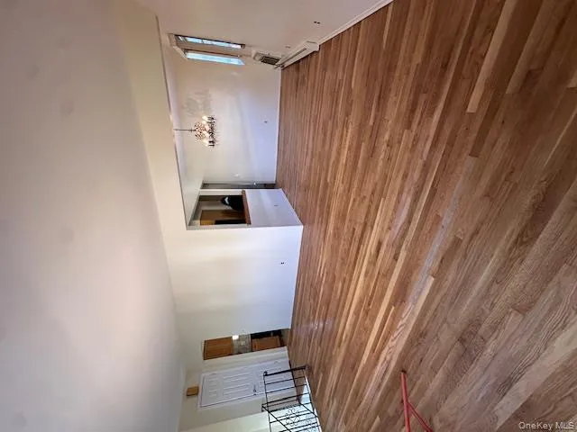 Unfurnished living room with wood finished floors, a chandelier, and baseboard heating Unfurnished living room with wood finished floors, a chandelier, and baseboard heating