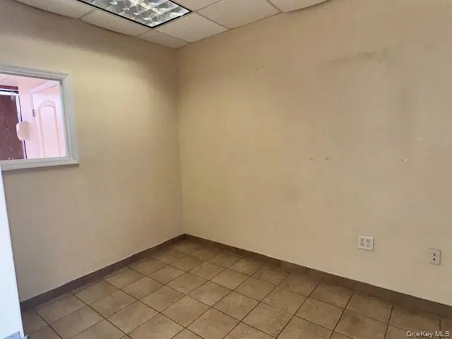 Empty room featuring a paneled ceiling and light tile patterned flooring Empty room featuring a paneled ceiling and light tile patterned flooring