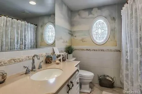 Full bath featuring tile walls, vanity, and curtained shower Full bath featuring tile walls, vanity, and curtained shower