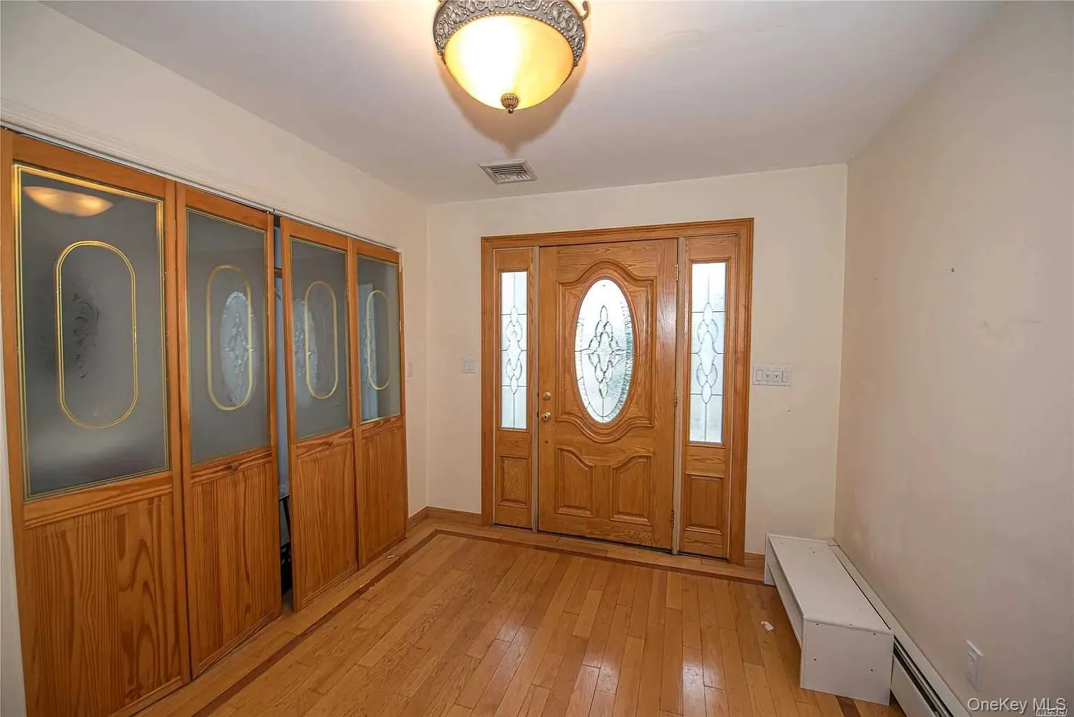 Entrance foyer featuring light wood-type flooring and a baseboard heating unit Entrance foyer featuring light wood-type flooring and a baseboard heating unit