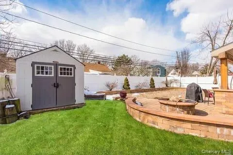 Fenced backyard with an outdoor fire pit, a storage shed, and a patio area Fenced backyard with an outdoor fire pit, a storage shed, and a patio area