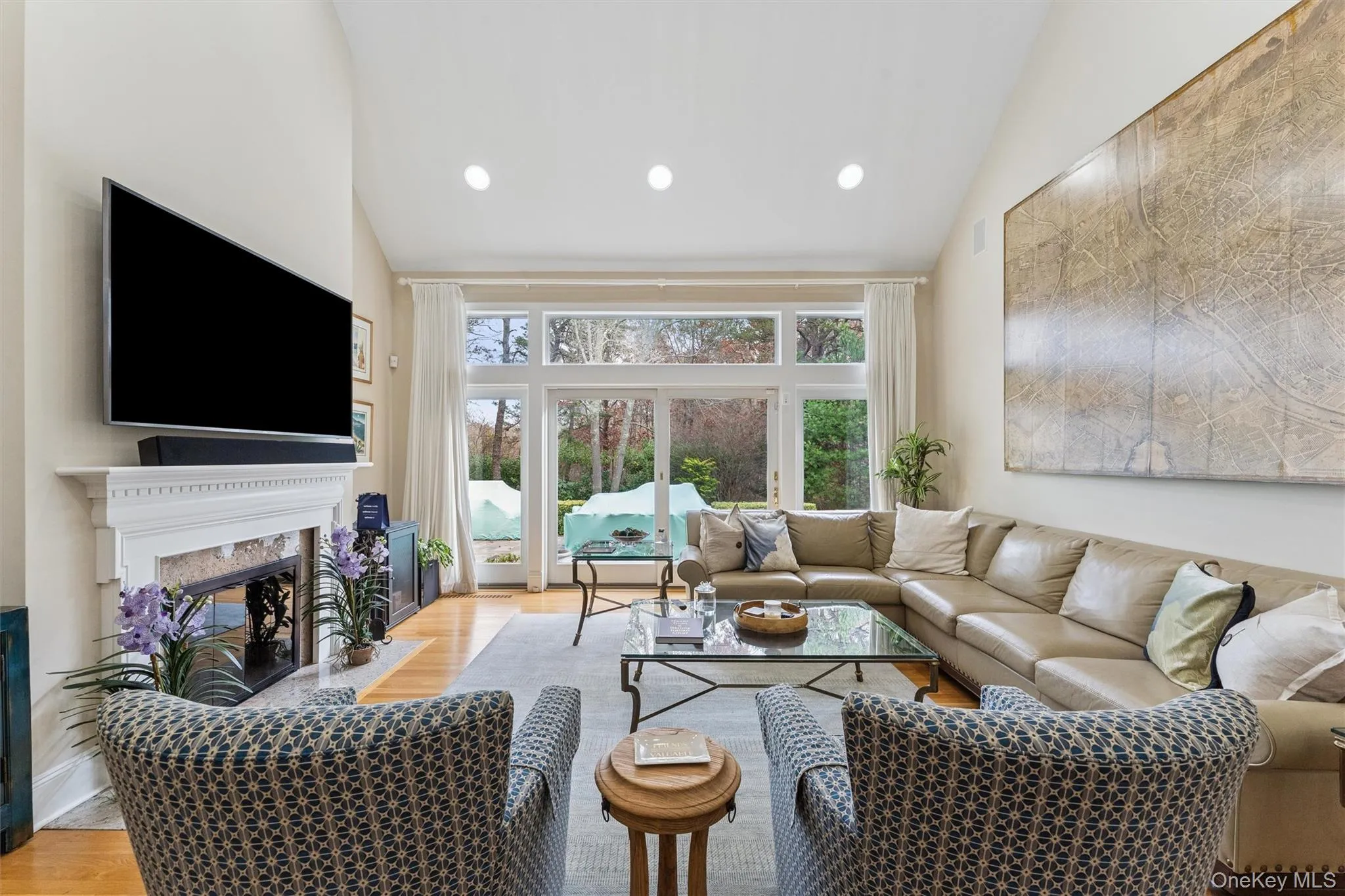 Living area featuring light wood-style floors, a premium fireplace, recessed lighting, and high vaulted ceiling Living area featuring light wood-style floors, a premium fireplace, recessed lighting, and high vaulted ceiling
